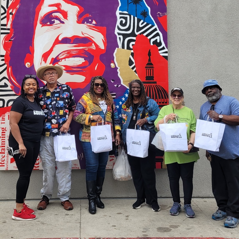 A group photo in front of a mural during the Black History Tour South LA